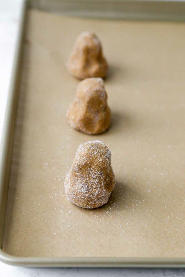 Top-heavy balls of cookie on a lined baking sheet.