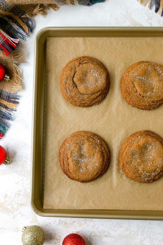 Baked molasses cookies on a lined baking sheet.