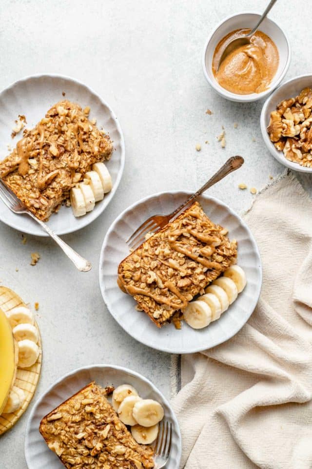 servings of banana baked oatmeal topped with almond butter on small white plates