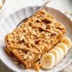 Serving of banana baked oatmeal drizzled with peanut butter on a white plate.