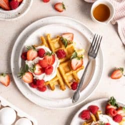 Belgian waffles topped with whipped cream, maple syrup and berries