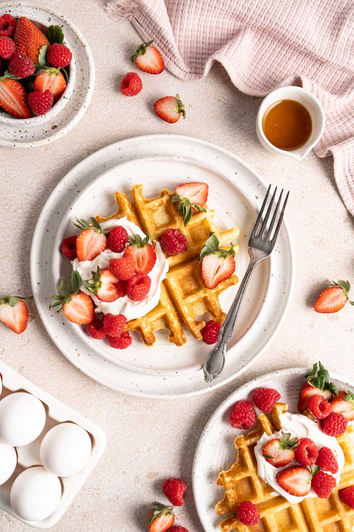 Belgian waffles topped with whipped cream, maple syrup and berries