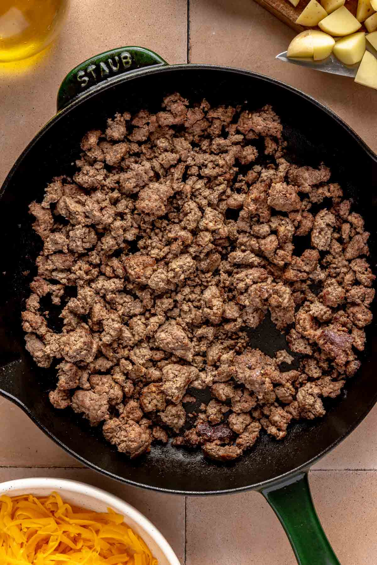 Browned ground beef in an iron skillet.