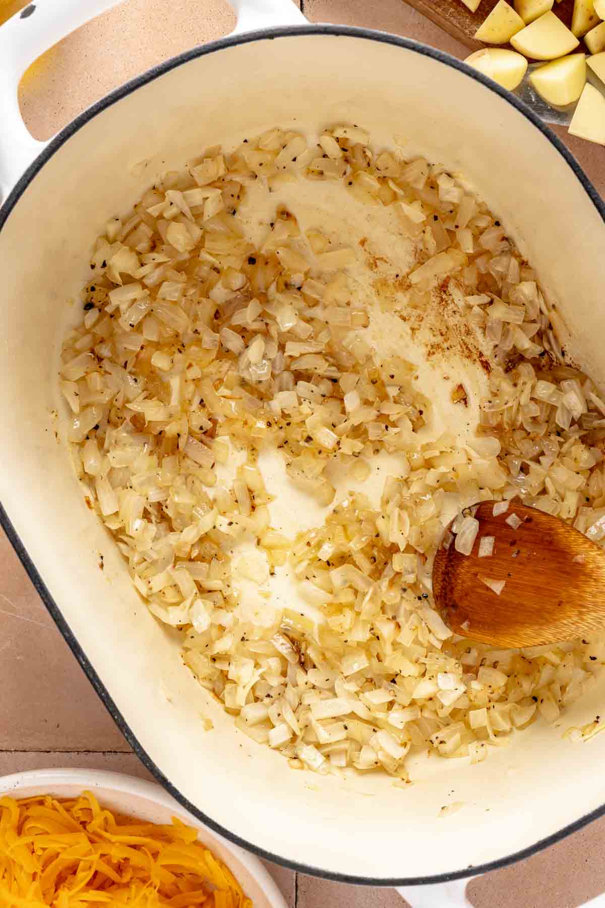 Sautéing onions in a large pot with a wooden spoon.