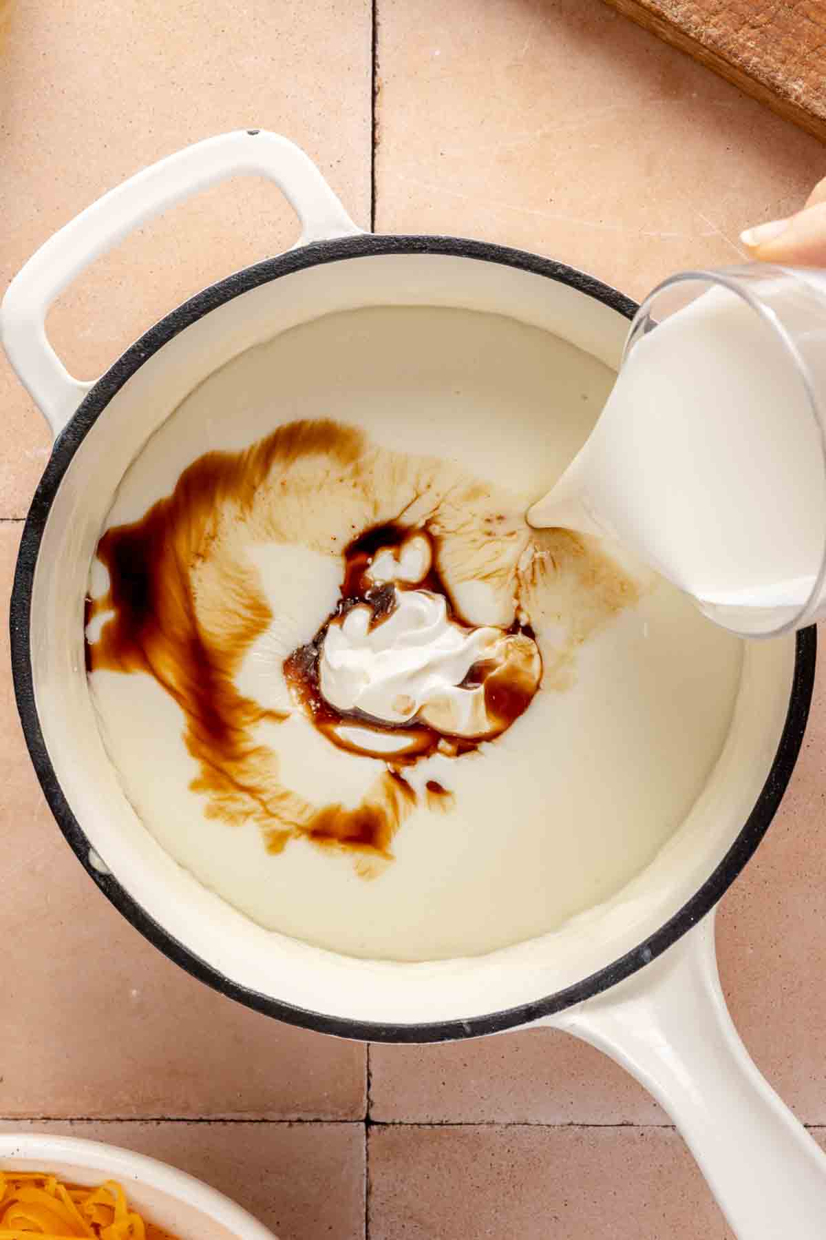 Pouring heavy cream, sour cream and Worcestershire sauce into roux.