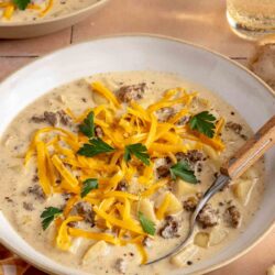 Cheeseburger soup topped with grated cheese and chopped parsley.