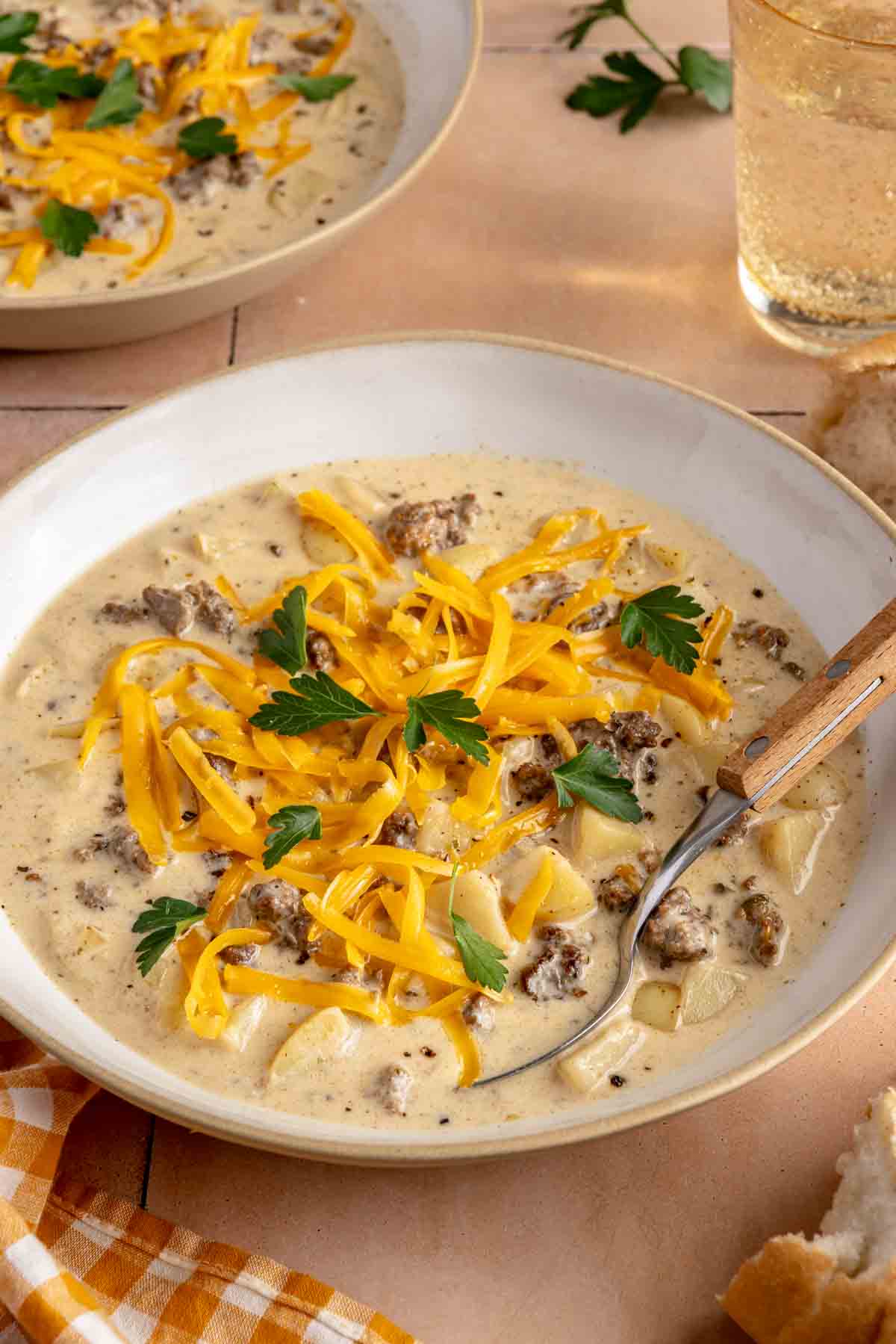 Cheeseburger soup topped with grated cheese and chopped parsley.