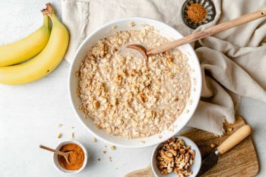 stirring oats with milk and mashed banana in a large white bowl