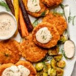 Salmon patties served with carrots and Brussels sprouts.