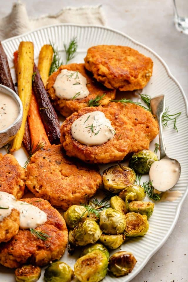 salmon cakes topped with sauce and served with veggies