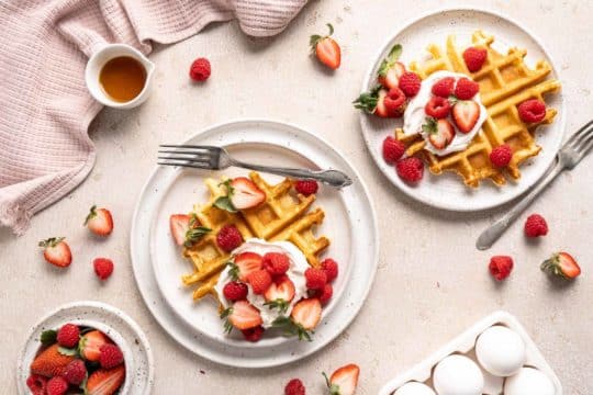 belgian waffles on white plates with strawberries and raspberries