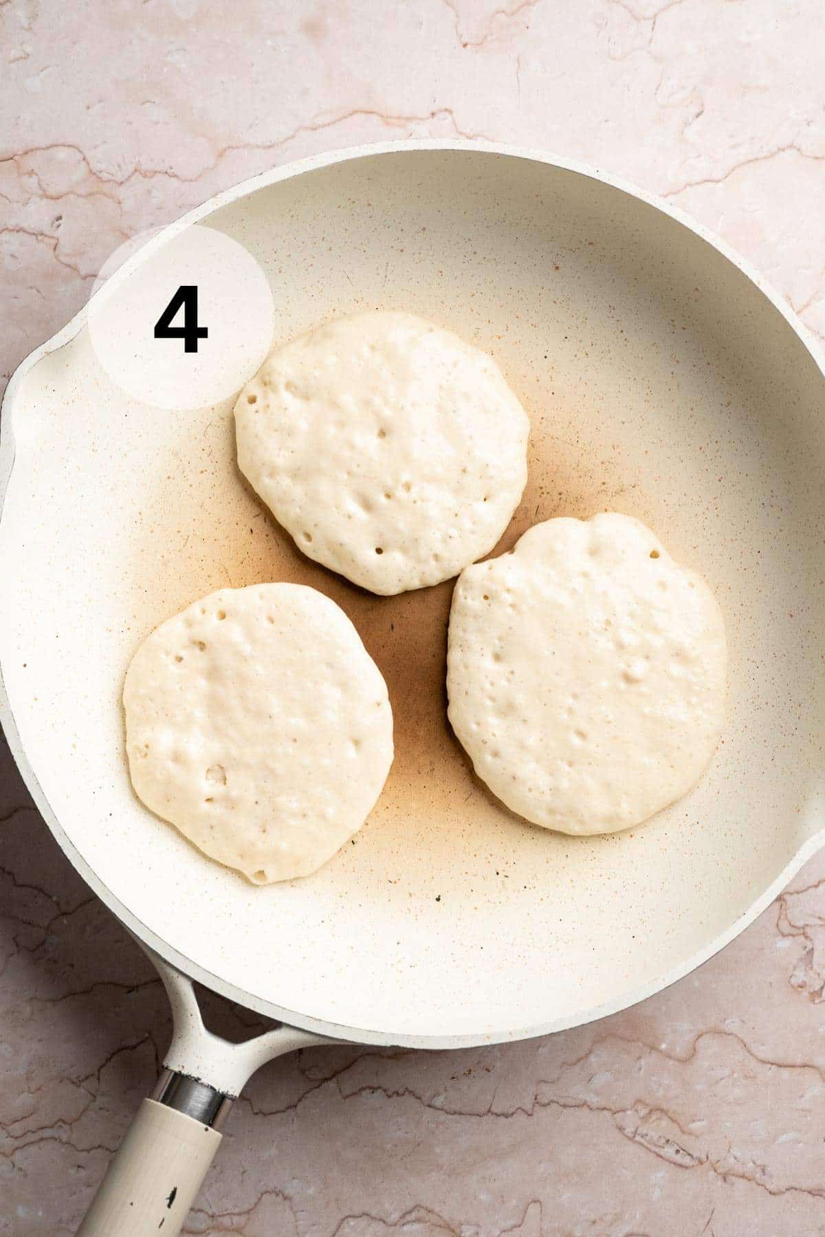 Pancakes cooking in a large skillet.