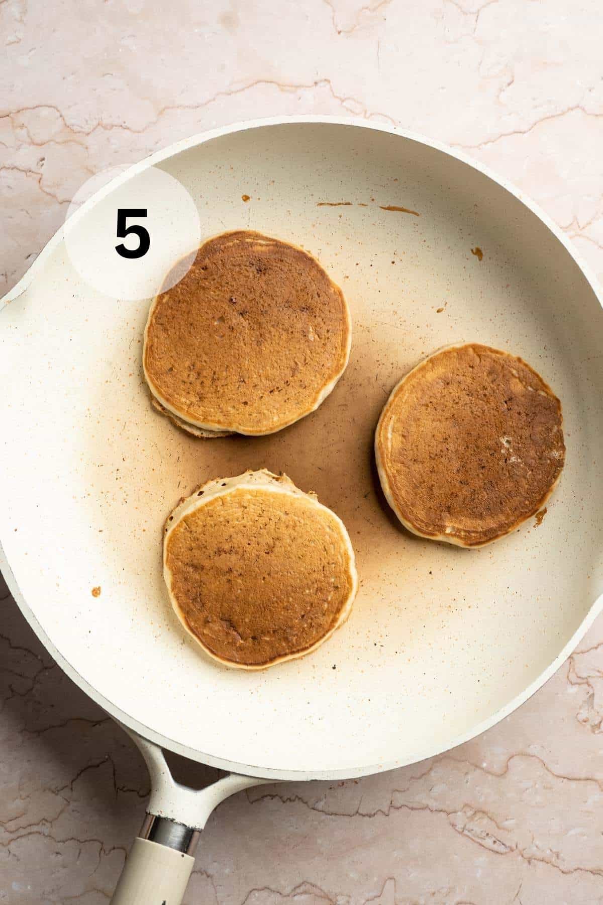 Flipping pancakes and cooking the other side in a skillet.