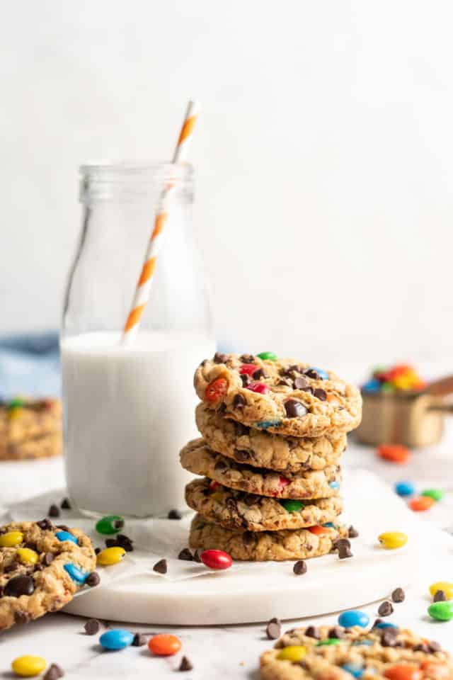 monster cookies stacked near a small jar of milk