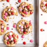Valentine's Day cookies on a baking sheet with pink, red and white M&M's.