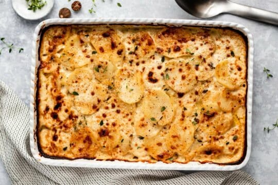 Baked scalloped potatoes in a white casserole dish.