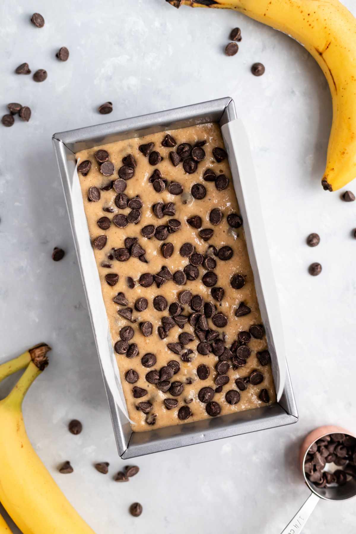Banana bread batter topped with chocolate chips in a loaf pan.