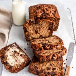 Chocolate Chip Banana Bread sliced on a bread board with a glass of milk.