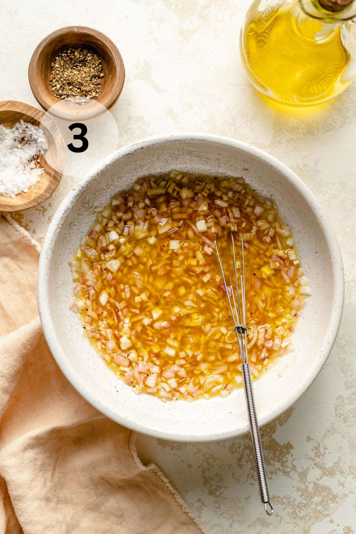 Whisking olive oil with shallots and vinegar.