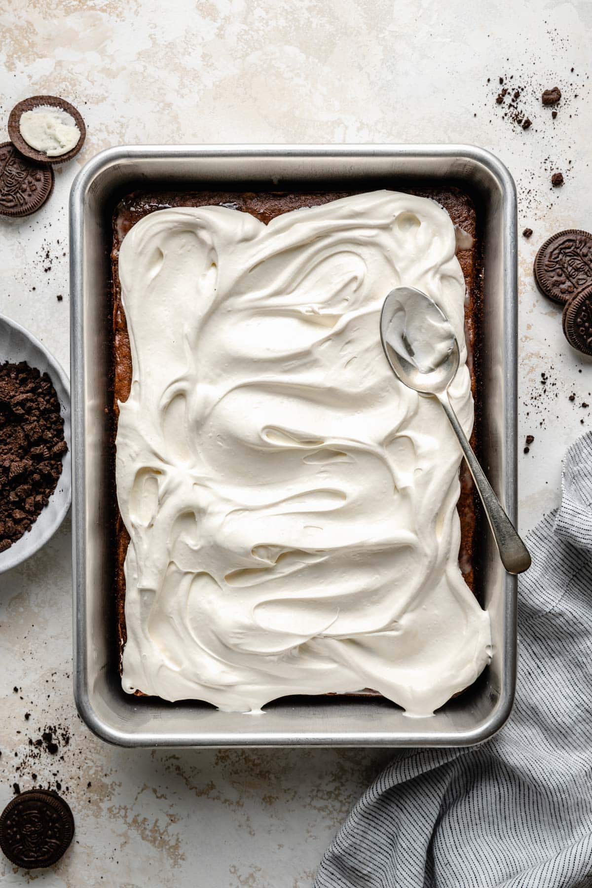 Spreading Cool Whip over a chocolate cake.