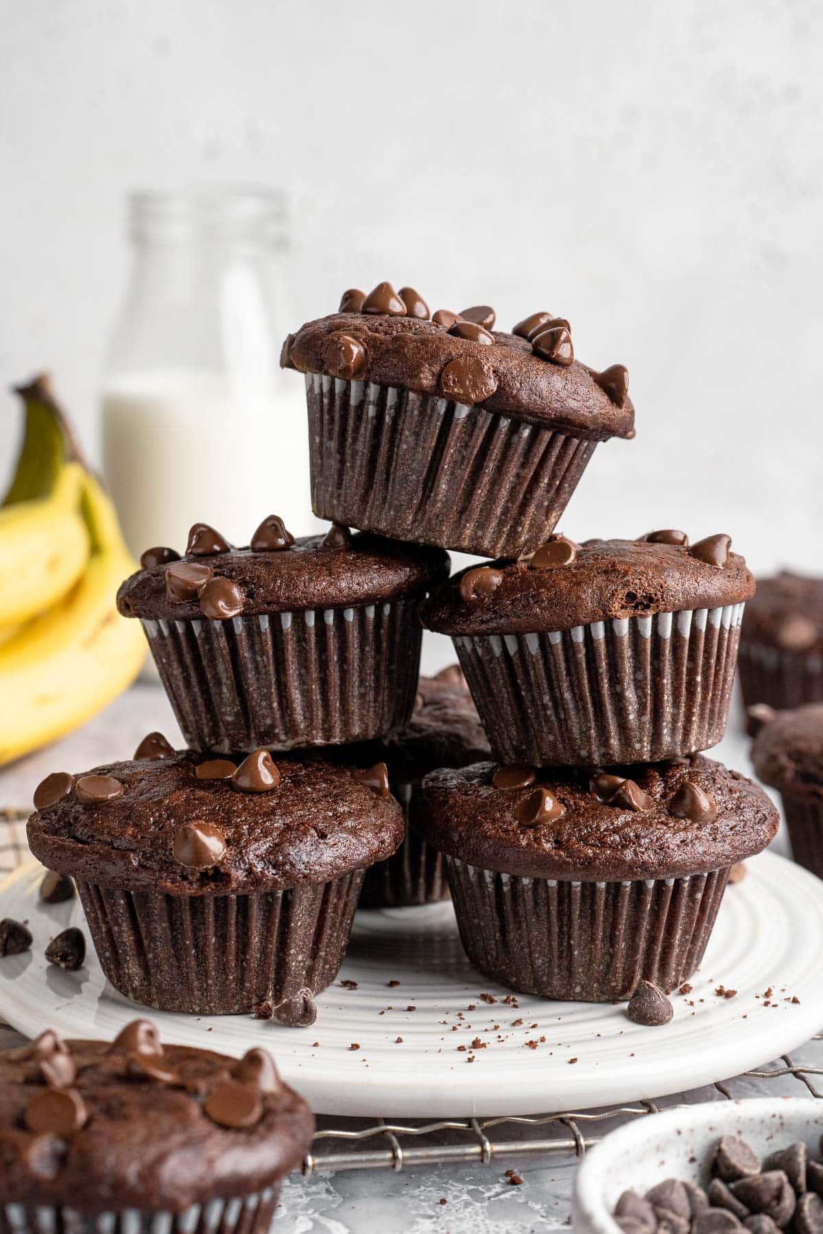 Chocolate chocolate chip banana muffin stacked on other chocolate muffins.
