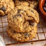 Oatmeal raisin cookies stacked on a wire rack, with a bite out of one.
