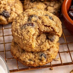 Oatmeal raisin cookies stacked on a wire rack, with a bite out of one.