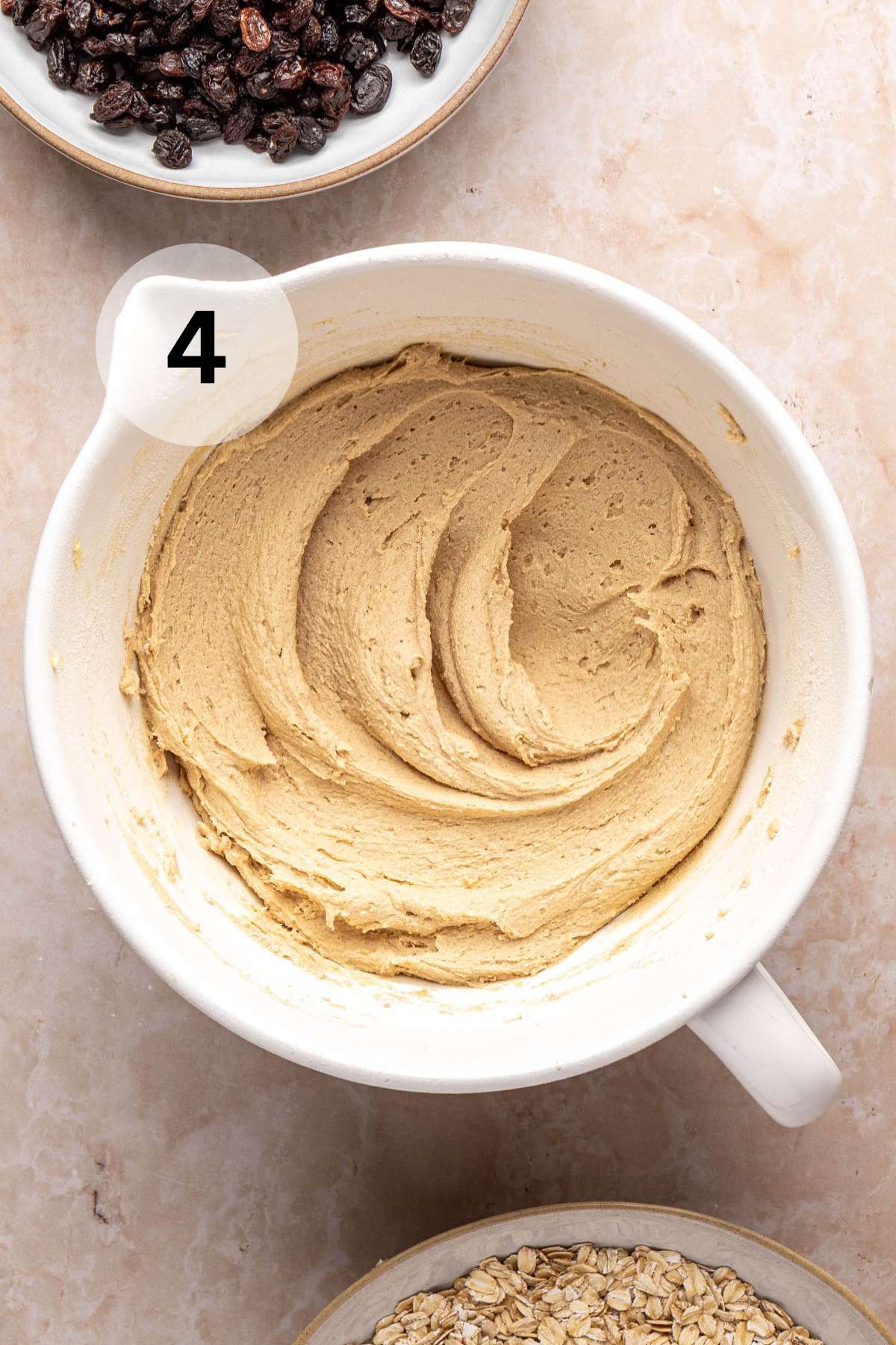 Cookie dough batter near a bowl of raisins.