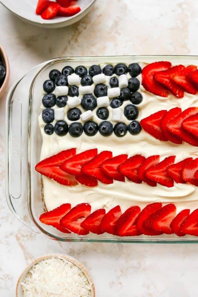 Adding sliced strawberries to the top of a flag cake.