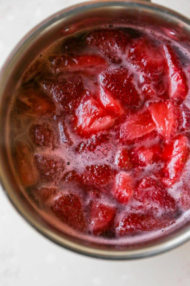 Cooking strawberries and sugar in a pot.