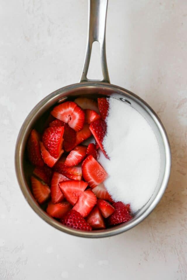 Fresh chopped strawberries and sugar in a saucepan.