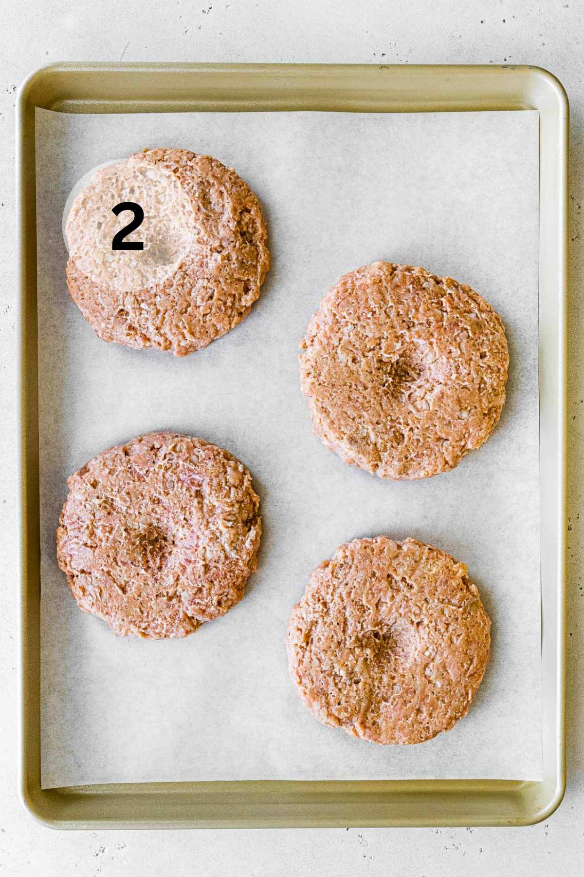 Ground turkey patties on a parchment lined baking sheet.