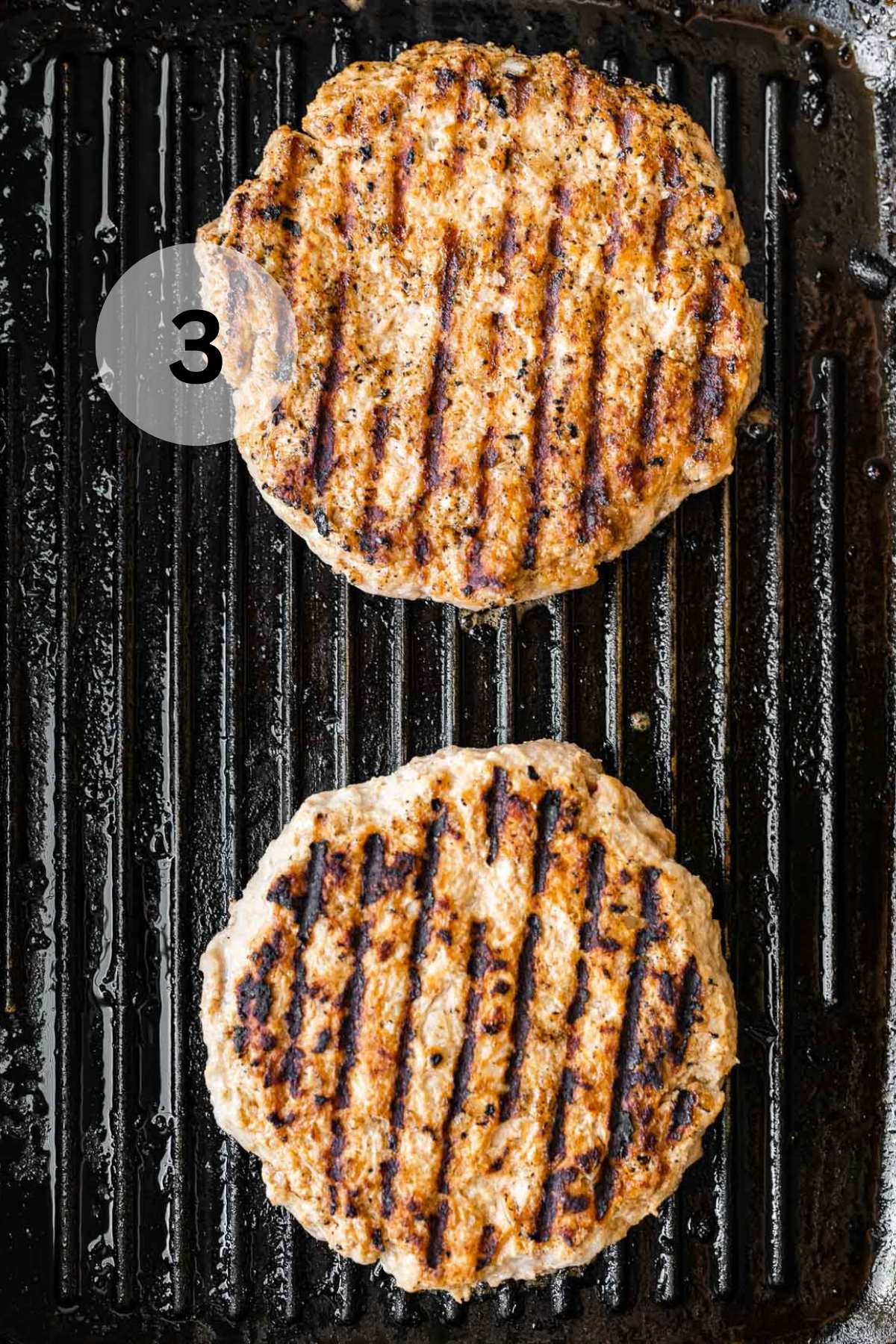 Burger patties cooking on a grill.