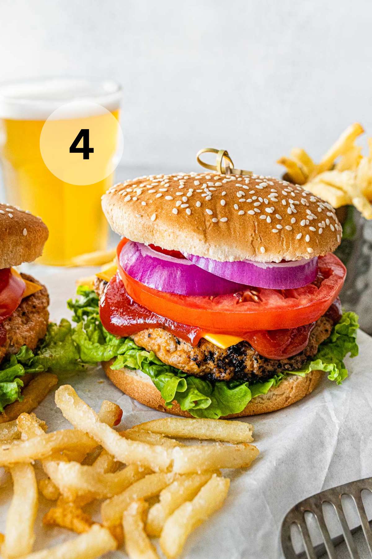 A burger with lettuce, cheese, tomato, onion and ketchup served with fries.