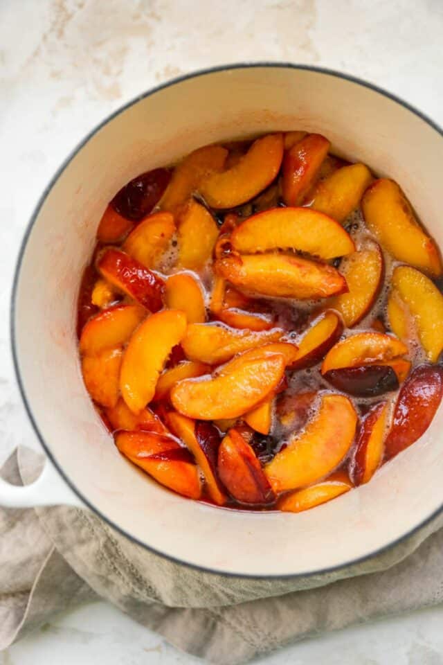 Peach slices cooking in a pot.