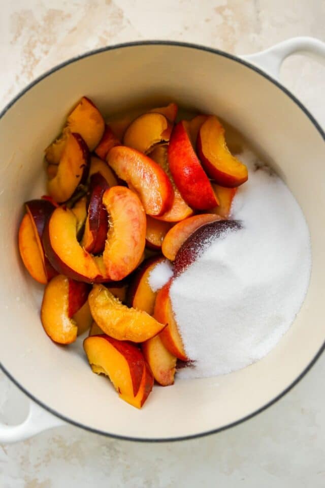 Sugar and peach slices in a large pot.