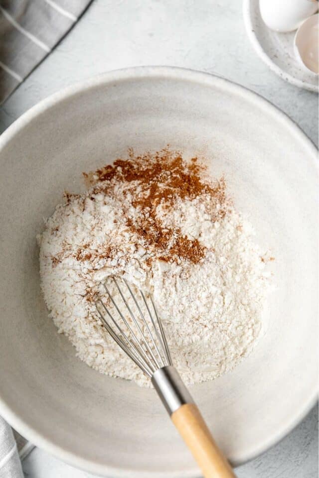Mixing flour with cinnamon and nutmeg in a large bowl.