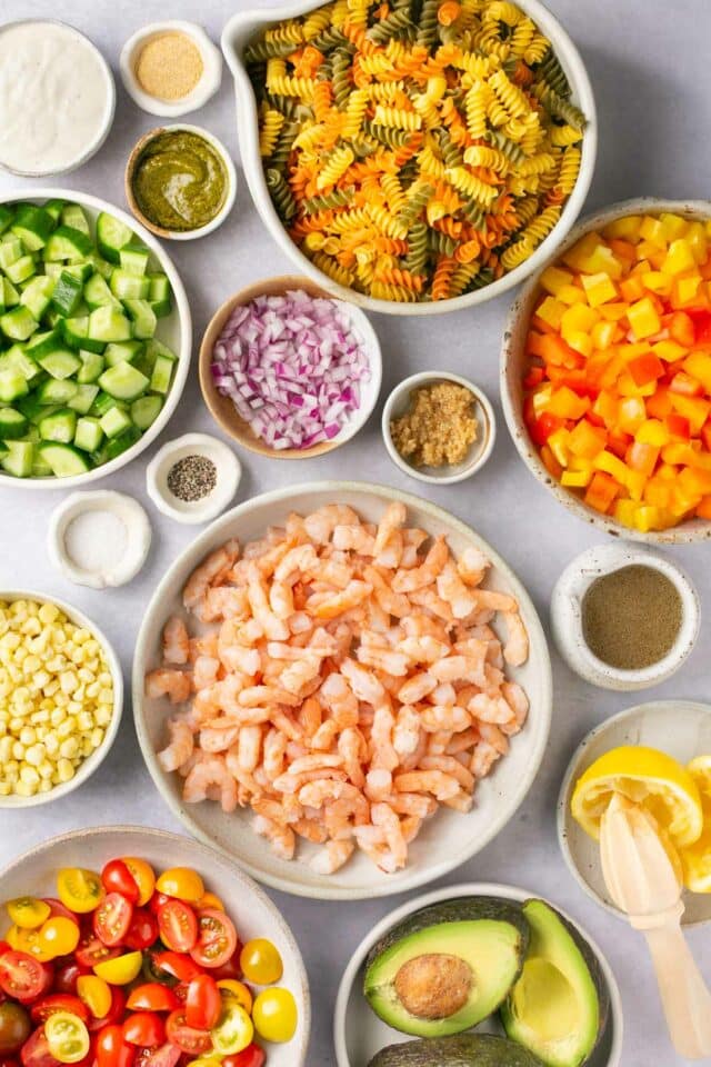 Ingredients for shrimp pasta salad divided into small bowls.