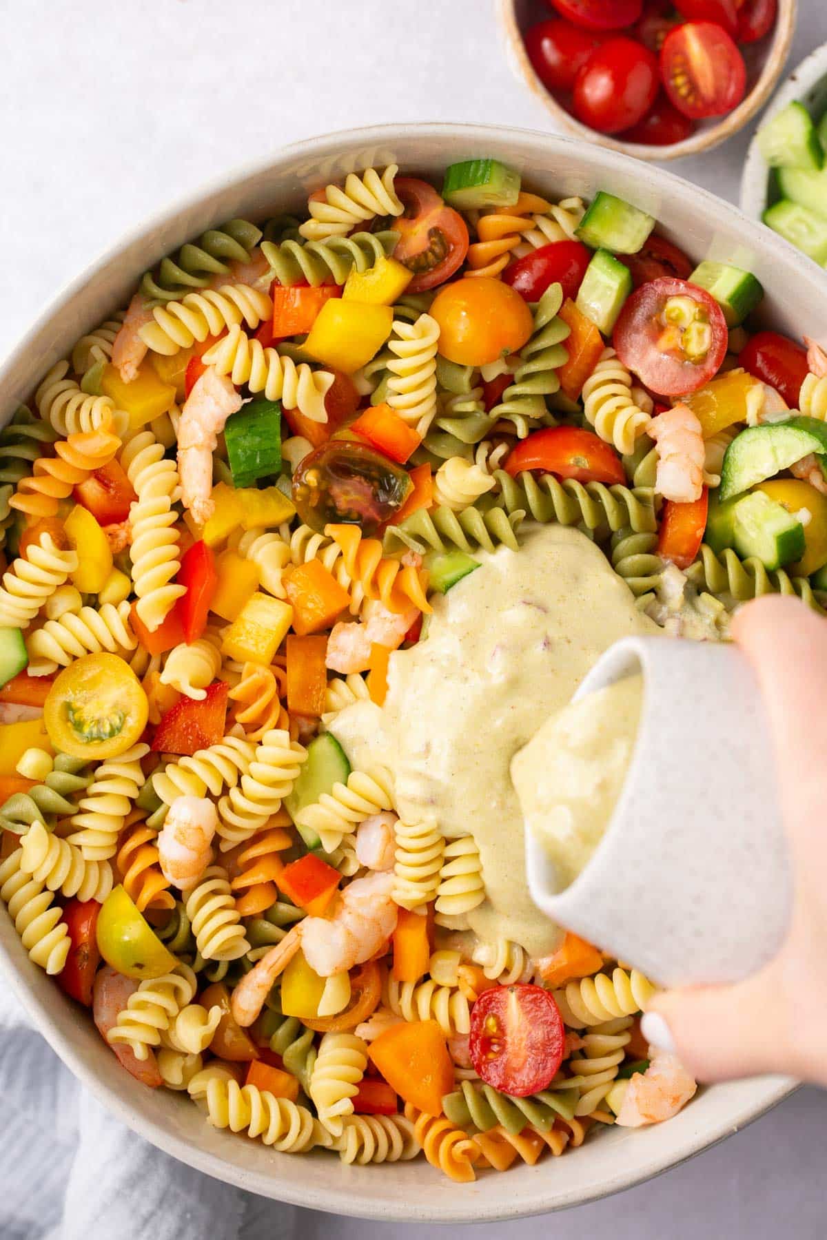 Pouring dressing over pasta salad.