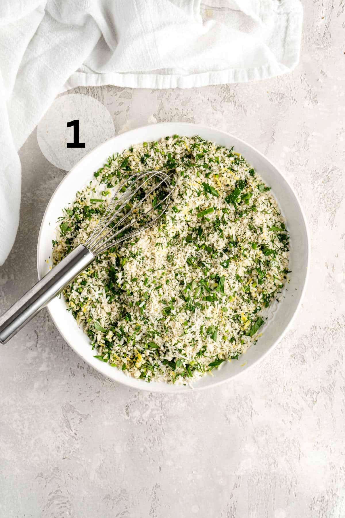 Stirring together breadcrumbs with herbs and lemon zest in a shallow bowl.