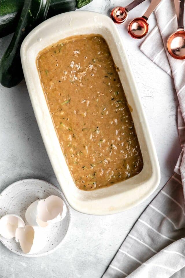 Adding zucchini bread batter to a loaf pan.