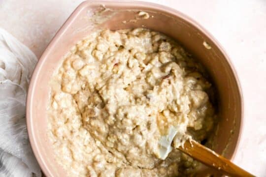 Combining wet ingredients with diced apple and flour in a bowl.
