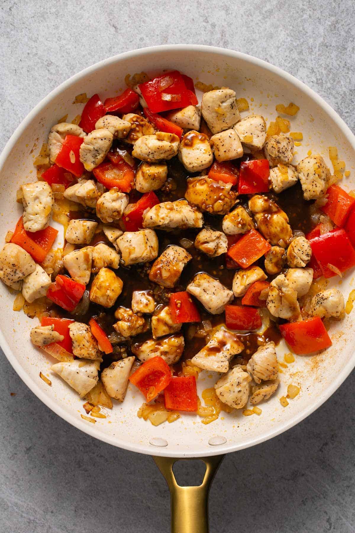Adding sauce to skillet with chicken and vegetables.