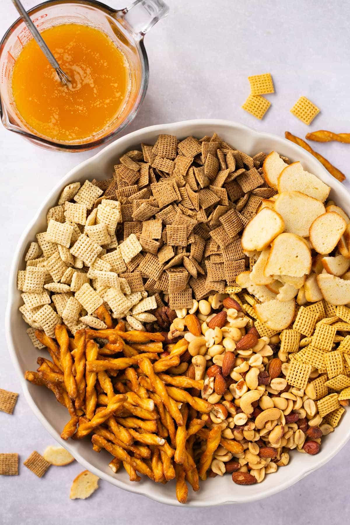 Adding crackers and cereal to a large bowl.