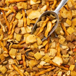 Chex Mix on a large baking sheet pan with a metal scoop.