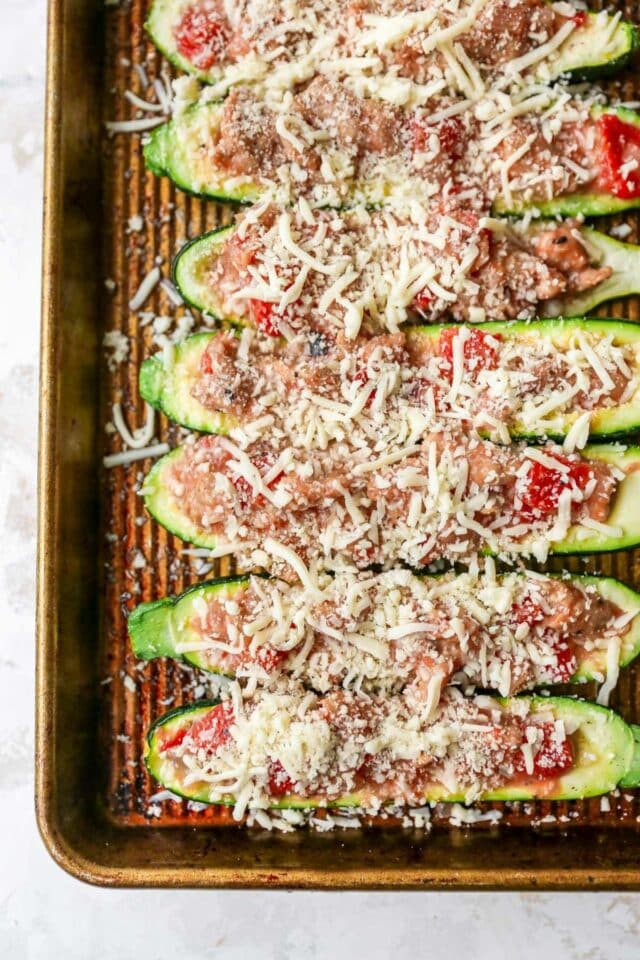 Filling zucchini with sausage and cheese.