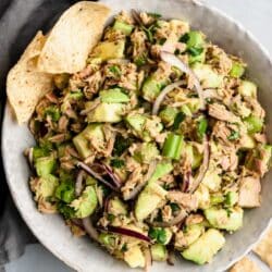 Bowl filled with avocado tuna salad near tortilla chips.