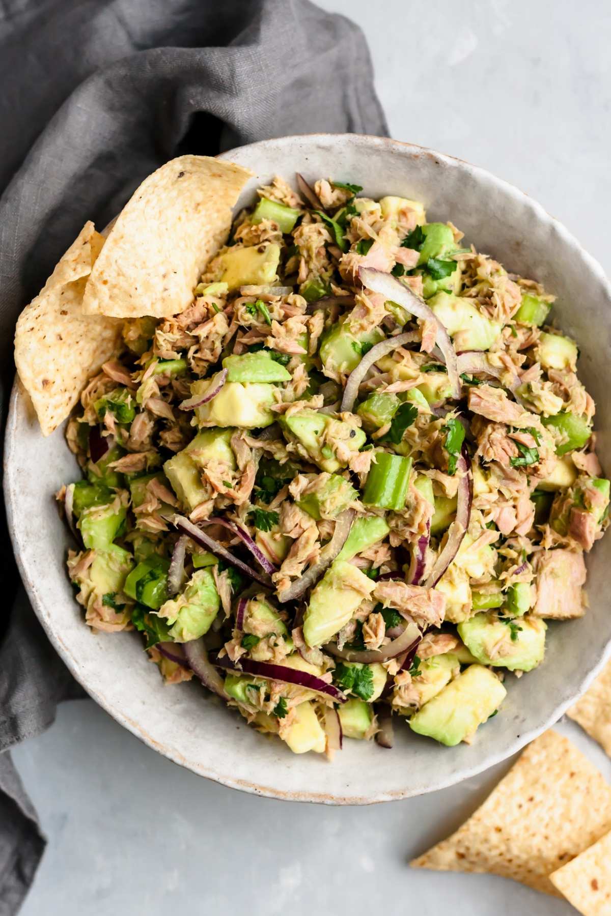Bowl filled with avocado tuna salad near tortilla chips.