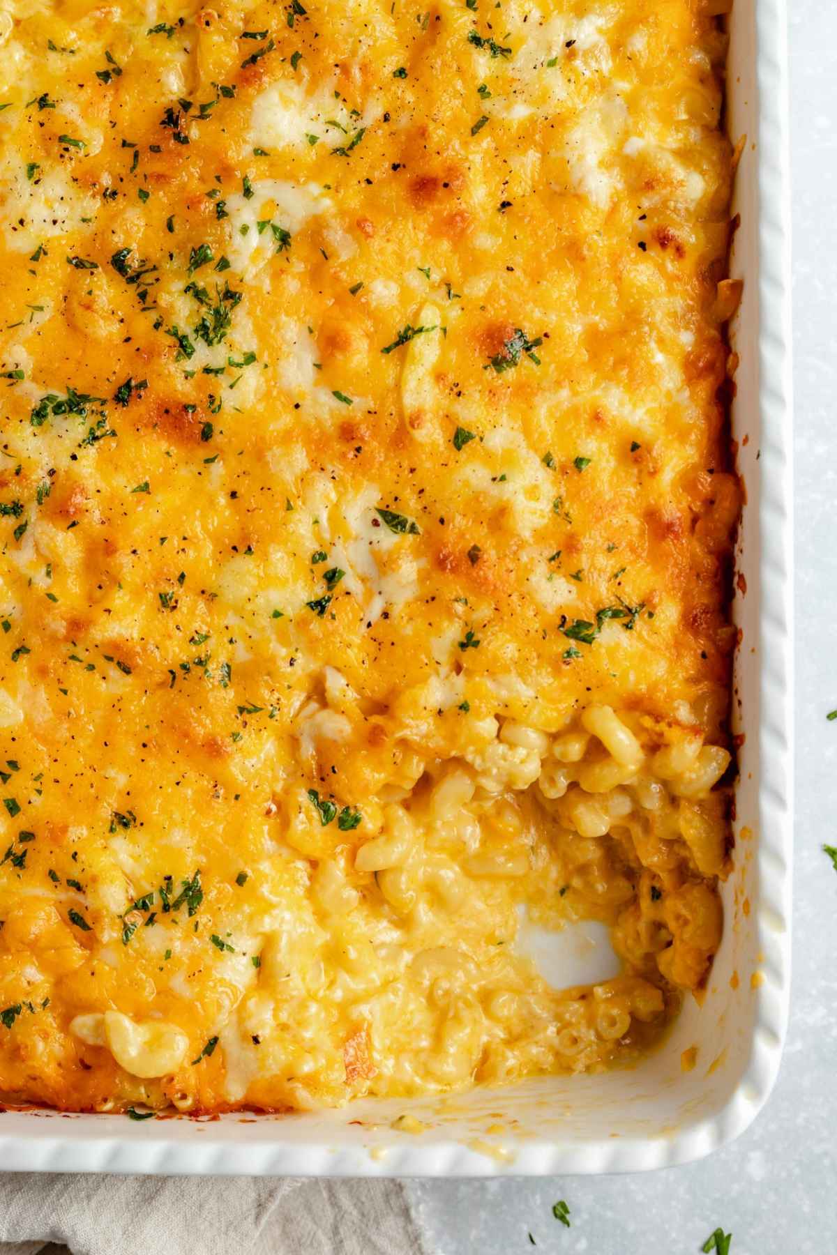 Casserole dish with a serving of macaroni and cheese dished out.