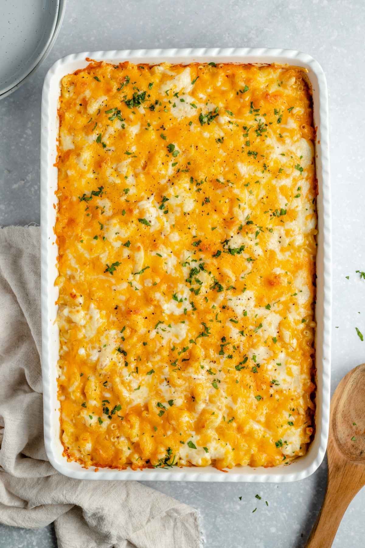 Baked Mac and cheese garnished with chopped parsley in white dish.